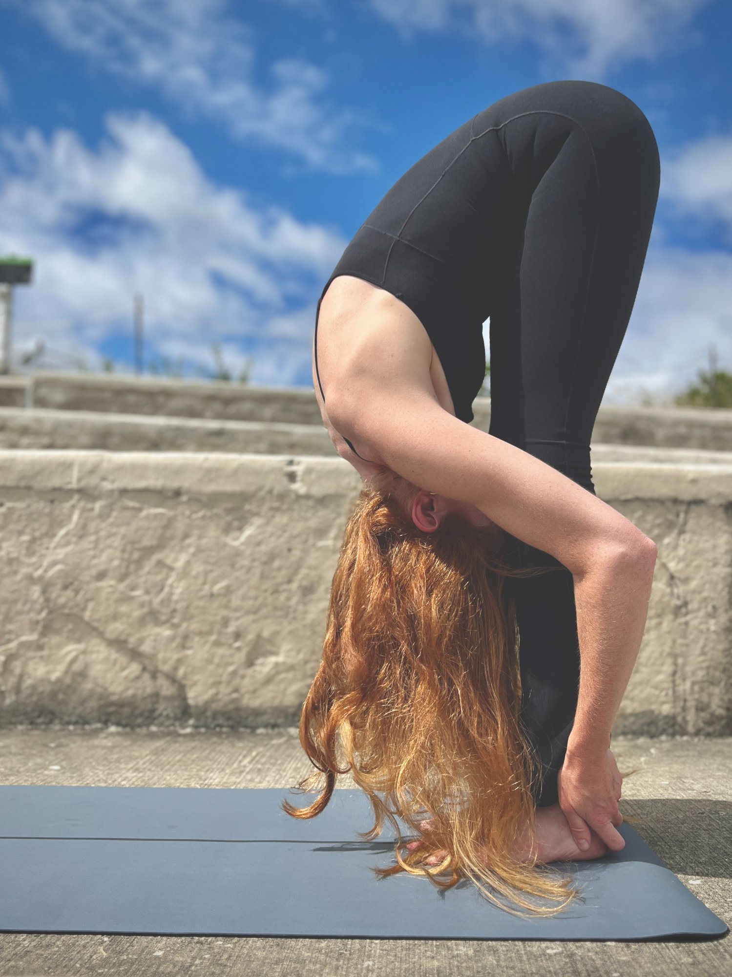 Kathryn Norris in standing forward fold, lakefront